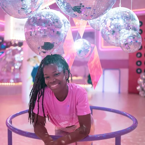 Photo of subject in pink shirt leaning forward with disco balls above her head
