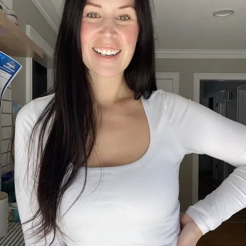 Headshot photo of a beautiful smiling brunette with hazel eyes wearing a white shirt with jeans
