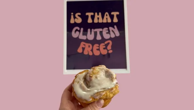 Cinnamon roll in front of a sign that says "is that gluten free?"