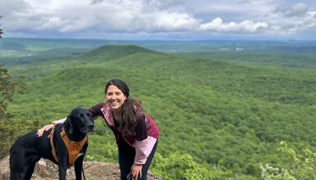 woman on mountaintop with black dog.