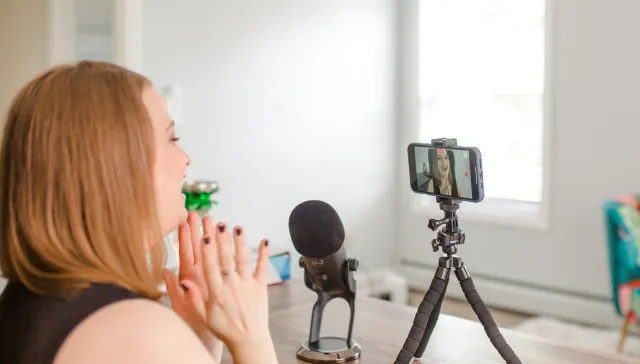 Lauren Simpson filming a video on the front facing camera of her iPhone with a Yeti microphone sitting on the desk next to it.