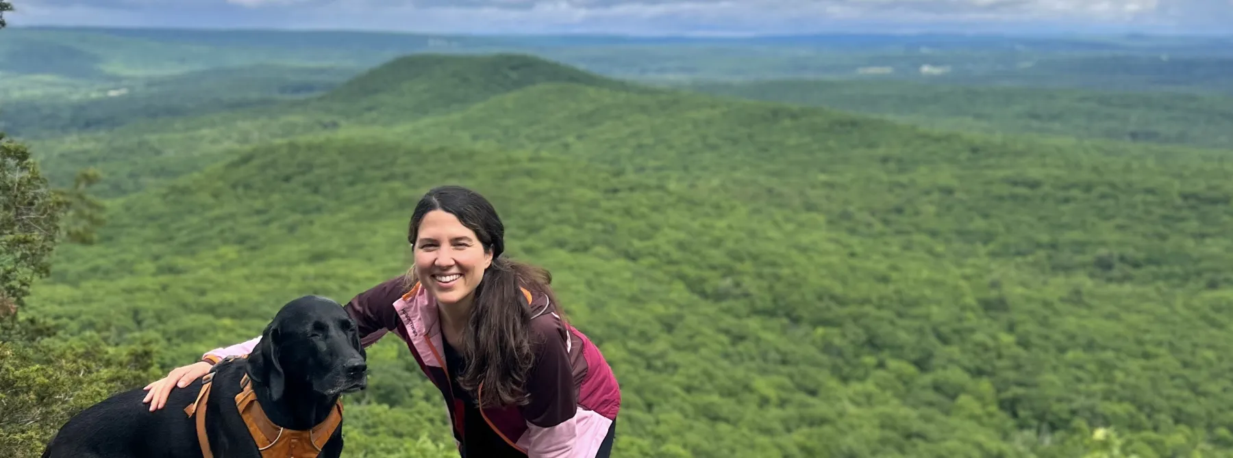 woman on mountaintop with black dog.