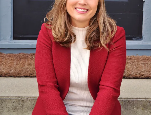 Woman wearing a red shirt and jeans sitting on cement stairs