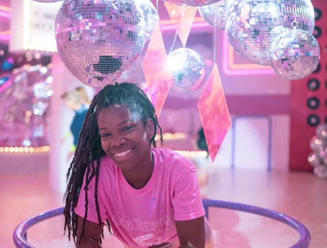 Photo of subject in pink shirt leaning forward with disco balls above her head