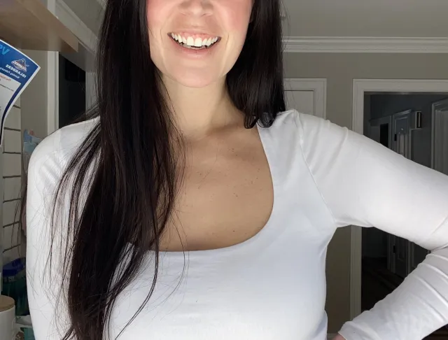 Headshot photo of a beautiful smiling brunette with hazel eyes wearing a white shirt with jeans